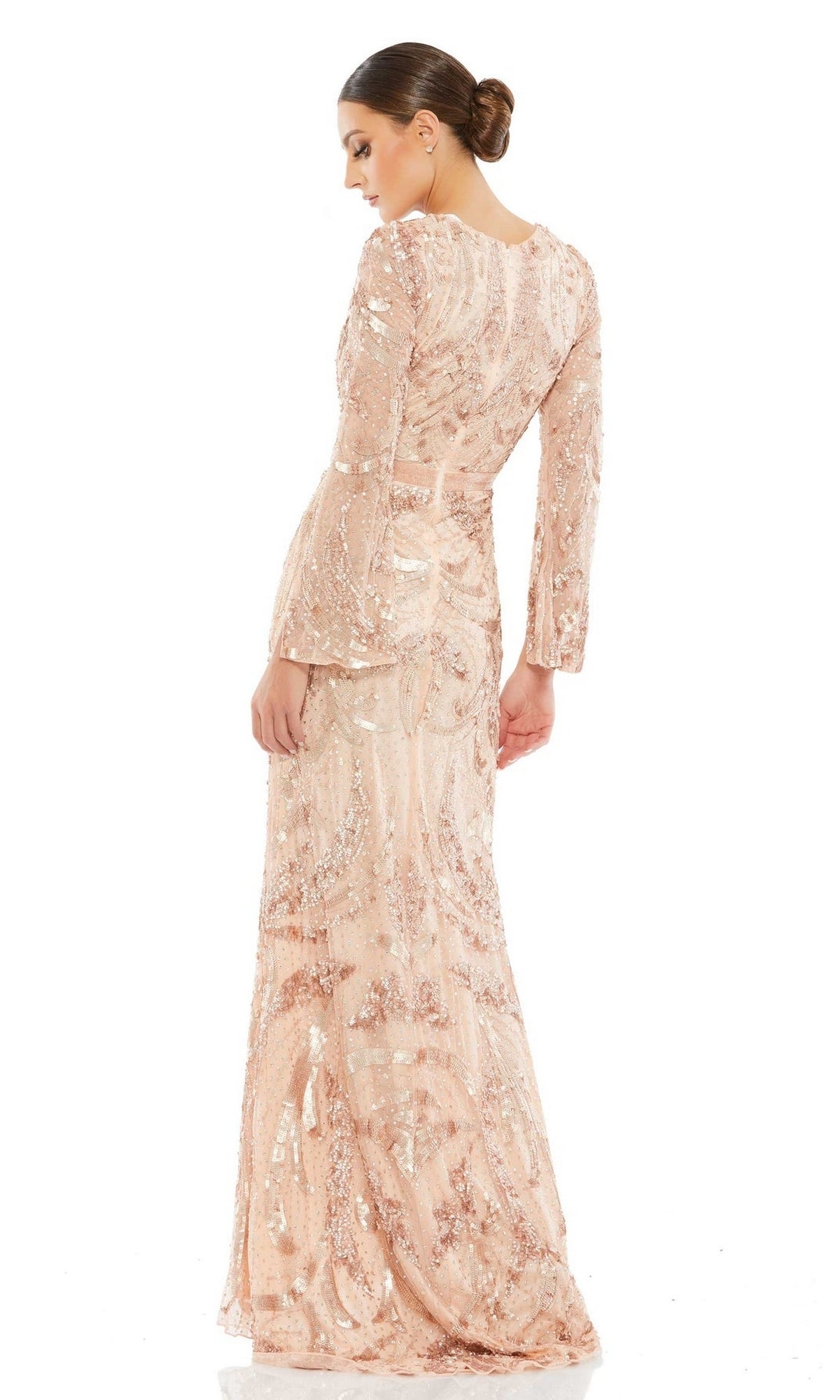 A woman models the Long Formal Dress 5222 by Mac Duggal— a light pink, long-sleeved, floor-length beaded gown with a fitted silhouette—posing with her back slightly turned against a white background.